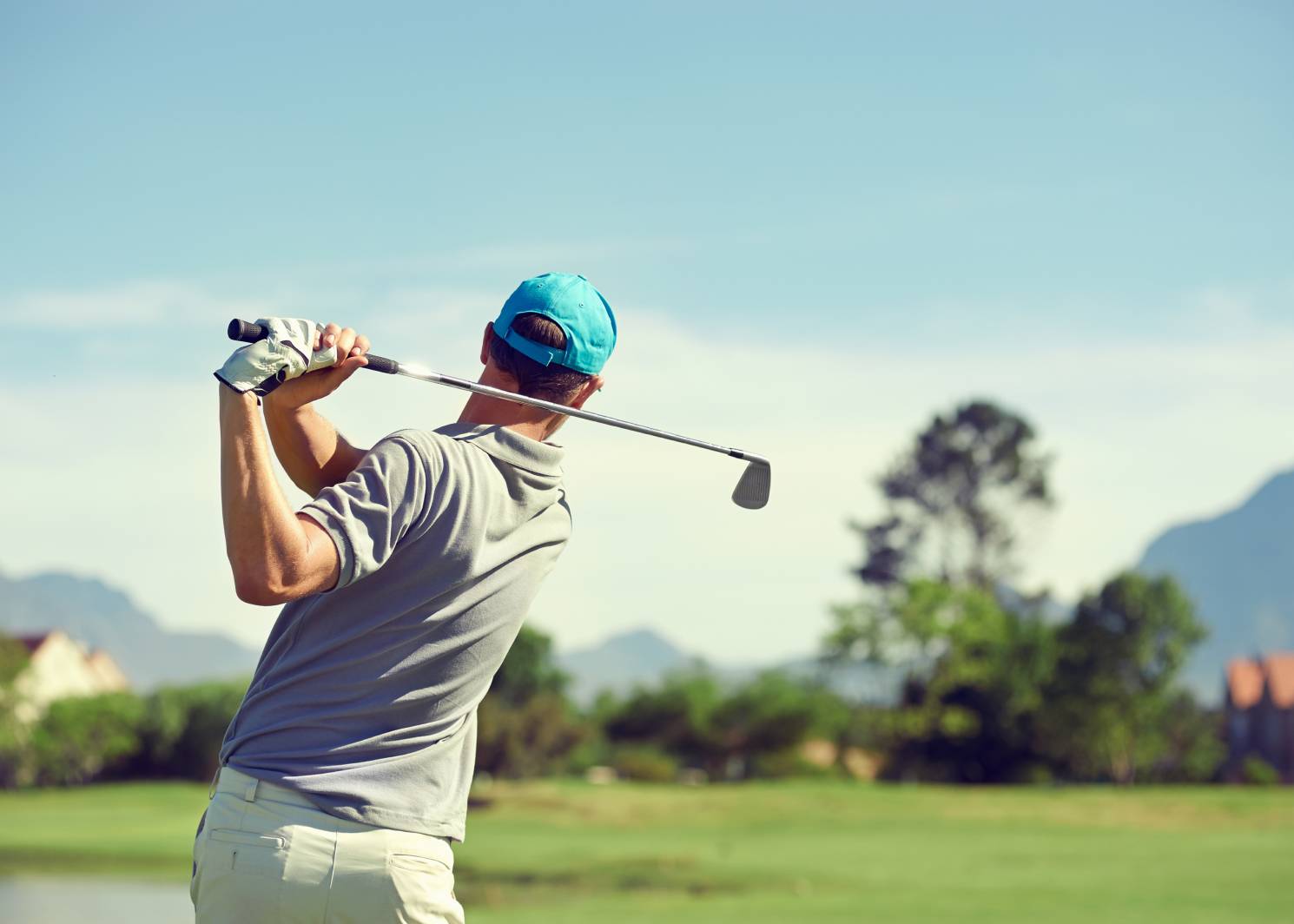 Golfer as seen from the back having just swung his golf club