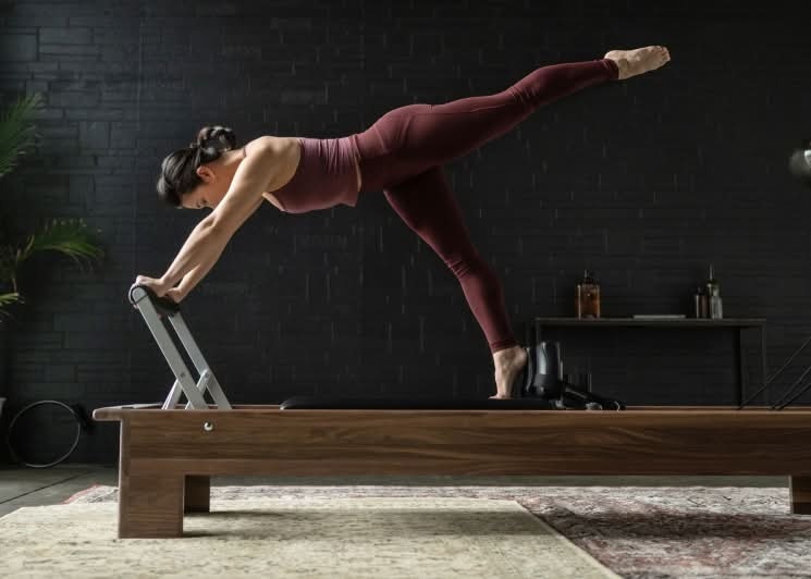 woman on walnut custom reformer